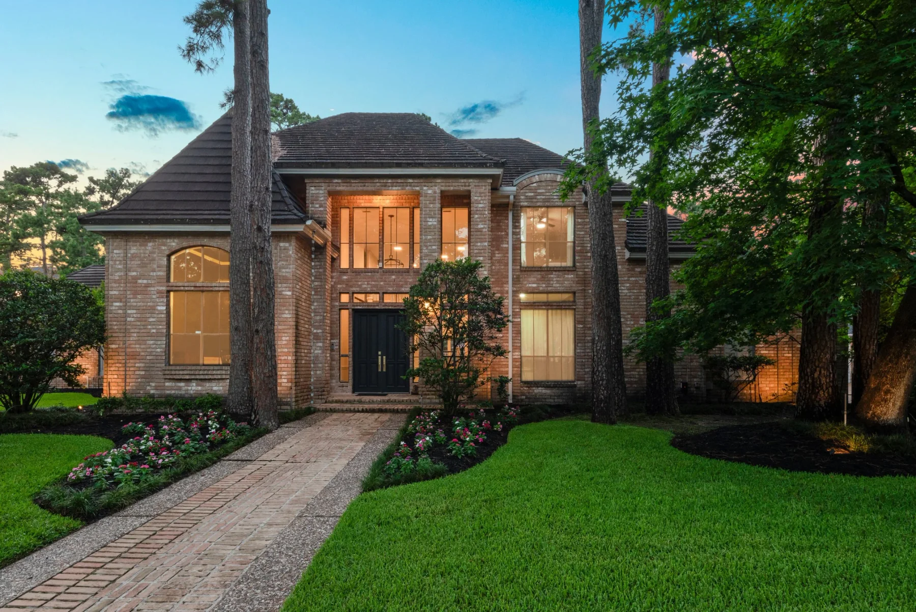 A brick home framed by mature trees at 9410 Windrush Drive, from the brokerage’s portfolio